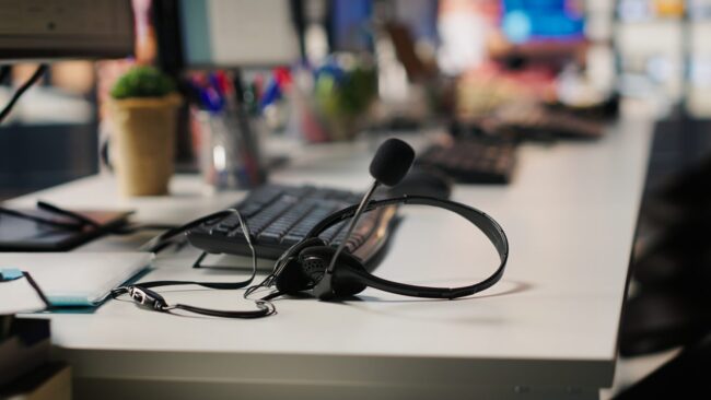 Audio equipment headset with mic used in customer support job workspace, closeup